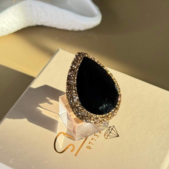 خاتم اسود اللون بشكل دمعة مرصع بشذرات ذهبية اللون و مطلي بماء الذهب
